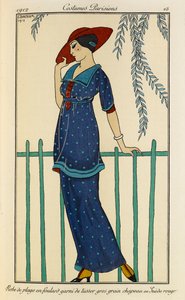 Robe de plage en foulard garni de tussor gros grain chapeau en Suède rouge. Costumes Parisiens no.15. Vrouw draagt een strandjurk en een ruwe zijden sjaal afgezet met grosgrain in gevlekt blauw en een rode hoed. door Georges Barbier