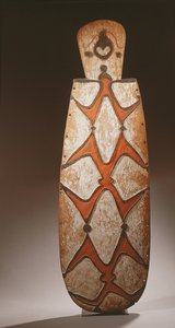 Ovale Asmat schild, gesneden in reliëf met gestileerde figuren, een masker bovenaan door Guinean New
