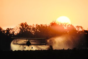 Crop duster tweedekker spuit pesticiden op een veld met gewassen langs de Mississippi rivier