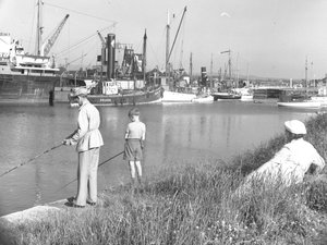 Een man en jongen vissen in Glasson Dock als een dame op zee; zeegezicht;ted achter kijkt toe, verschillende boten aangemeerd door Joseph Hardman