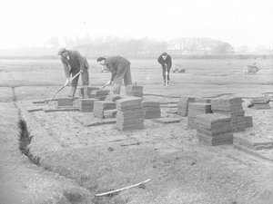 Graszodensnijders die graszoden snijden, tillen en stapelen door Joseph Hardman