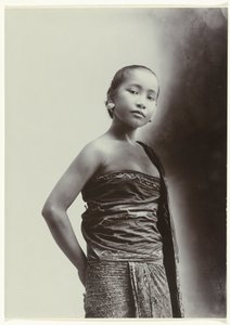 Studioportret van een jonge Javaanse vrouw in een sarong met batik motief