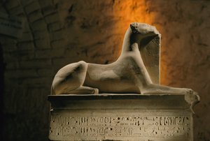 Kalkstenen beeld van de jakhalsgod Anubis geknield op een basis in de vorm van een sarcofaag, 2002 door Kenneth Garrett