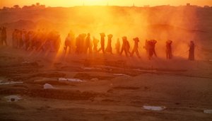 Arbeiders dragen materialen bij archeologische opgraving in Abydos