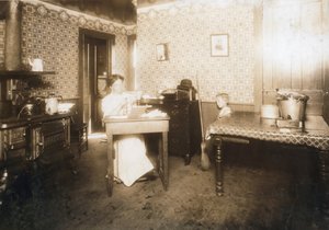 Vrouw die borstelharen in tandenborstels steekt in haar keuken, c.1912