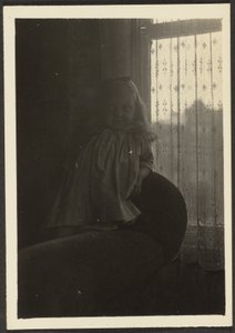 [Klein meisje leunend op de rugleuning van een stoel]. door Louis Fleckenstein