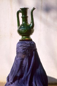 Vrouw in Kabul afgeschermd door zijden chadri, draagt kruik door Thomas J. Abercrombie
