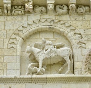 Romaans kunst: detail van de gevel die Hugues de Surgeres en Geoffroy de Vendome of keizer Constantijn de Grote afbeeldt, wiens paard de ketterij vertrapt en Christus triomfeert over het kwaad en de dood, Notre Dame de Surgeres