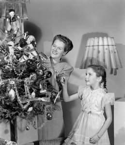 Vrouw en meisje versieren een kerstboom, ca. 1948 door Unbekannt