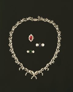 Art Deco ketting met rol- en bladontwerp; robijn- en diamantbaguettring; saffier- en diamantdriesteenring; smaragd- en diamantdriesteenring