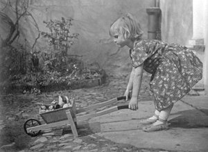 Klein meisje speelt met een kruiwagen. Fotografie rond 1931