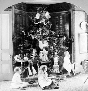 Kinderen verzameld aan de voet van de boom omringd door cadeaus op kerstochtend. door Unknown photographer