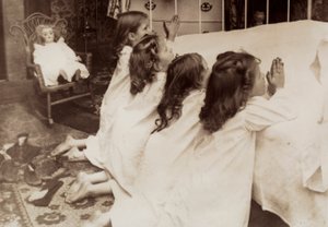 Vier kleine meisjes knielen aan de zijkant van een bed terwijl ze hun avondgebed zeggen door Unknown photographer