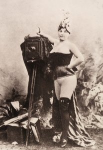 Portret van een gedeeltelijk naakte vrouw leunend op een antieke camera. door Unknown photographer