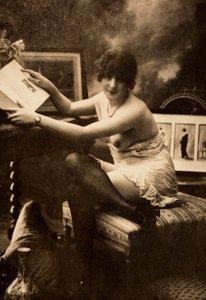 Portret van een jonge vrouw in intieme kleding, zittend aan een tafel met een boek door Unknown photographer