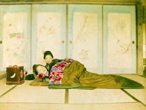 Liggend op een futon. Twee Japanse vrouwen liggen op een traditionele futon op de vloer. Japan, circa 1910.
