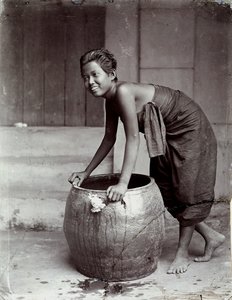 Jonge glimlachende Thaise vrouw, duwt een grote container door Unknown photographer