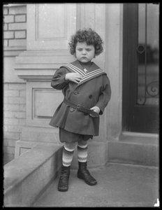 Kleine jongen in matrozenpak op de stoep van een appartementengebouw aan Vermilyea Avenue, ca. 1913
