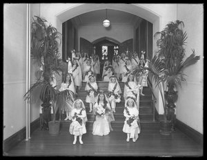 Kleine meisjes in het Rooms-Katholieke Weeshuis, Kingsbridge, Bronx, terugkomend van de kapel in witte jurken met kransen en slingers, 20 oktober 1914 door William Davis Hassler