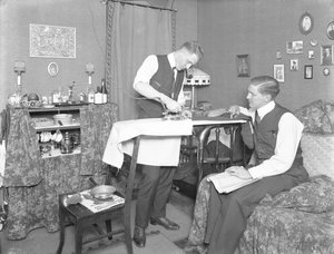 Onbekende man demonstreert het gebruik van een elektrisch strijkijzer, bekeken door een andere man, c.1913-14