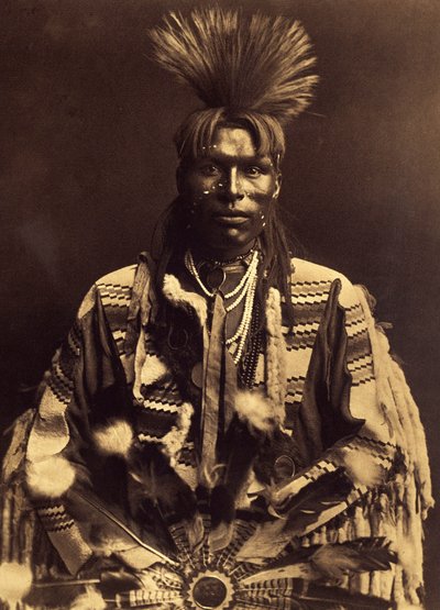Een dandy piegan. Rond 1855 begonnen de jonge mannen een scheiding in hun haar te maken van de ene slaap naar de andere en hun rug te krullen met een voorverwarmde geweerstok. door Edward Sheriff Curtis