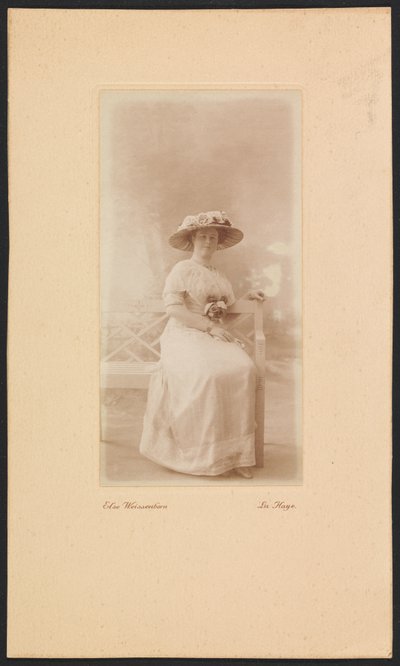 Portret van mevrouw M.C. Lucassen-Van Idsinga met hoed en jurk zittend op een bank door Else Weissenborn
