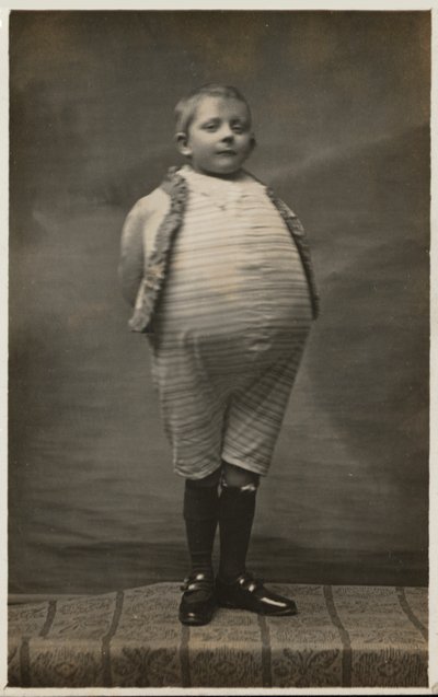 Schooljongen, verkleed om een zeer grote buik te hebben door English Photographer