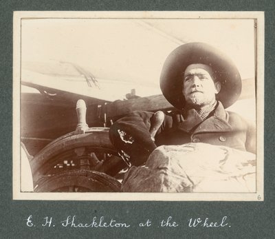 E H Shackleton staand bij het stuur van de 