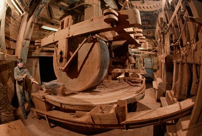 Een man maalt cacaoboonenschillen voor diervoeder in een 100 jaar oude molen. Ooievaar Molen door James L Stanfield