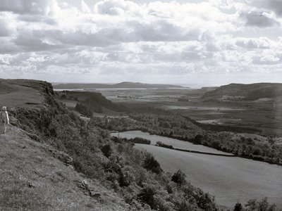 Een dame staat op een heuvel en kijkt uit over het landschap bij Scout Scar door Joseph Hardman