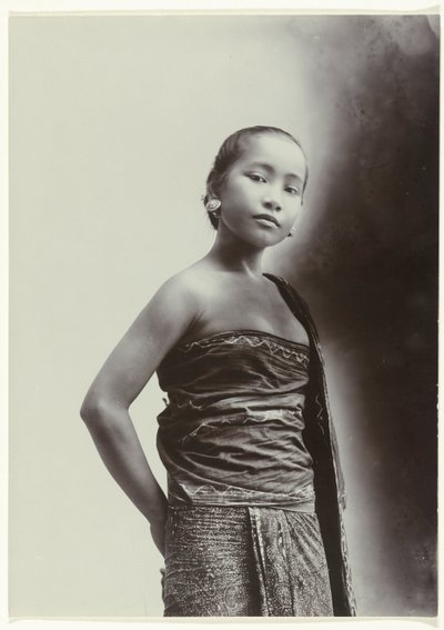 Studioportret van een jonge Javaanse vrouw in een sarong met batik motief door Kassian Cephas