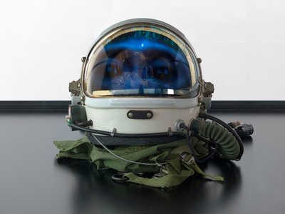Alpha Omega, 2016 (Glas, LCD-scherm, mediaspeler, replica schedel, ruimtehelm, hout) door Mat Collishaw