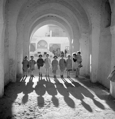 Europese kinderen in schooluniform onder boog met schaduwen door Maynard Owen Williams