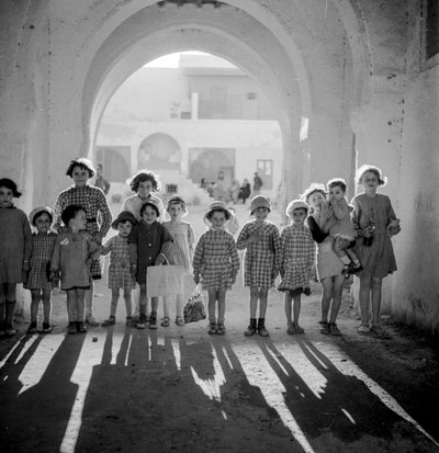 Europese kinderen in schooluniform onder boog met schaduwen door Maynard Owen Williams