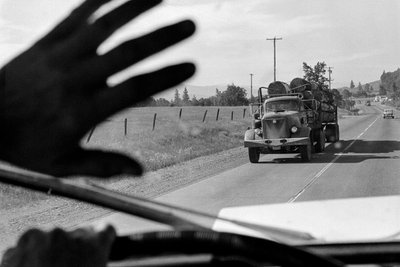 Bestuurder in vrachtwagen met hout zwaait naar een andere vrachtwagen met hout door Ted Spiegel