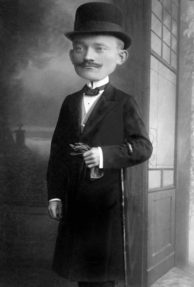 Portret van een zeer elegante man met een reuzenhoofd, hij draagt een bolhoed, een wandelstok, een vlinderdas en een zwarte jas. Dit is een fotomontage. Jaren 1910 Historische foto, man met een reuzenhoofd door Unbekannter Künstler