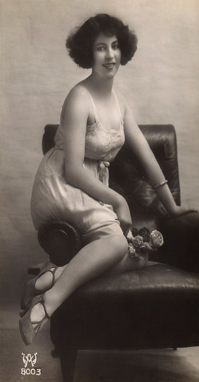 Een jonge vrouw poserend in haar onderjurk, zittend in een fauteuil door Unknown photographer