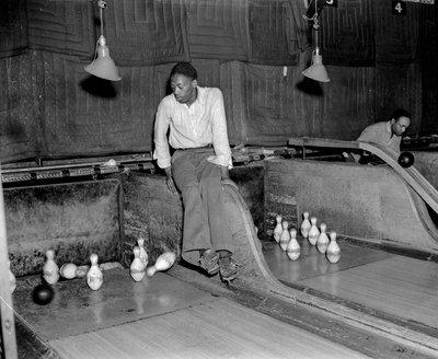 Afrikaans-Amerikaanse man bij bowlingbaan, handmatig de kegels opnieuw opzetten door Volkmar Wentzel