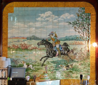 Interieur, tegelpaneel, schilder Furcy Ernest Tondeur, uitvoerder Boch Frères La Louvière, tweede paneel toont jachtscène met galopperende ruiter met jachthoorn door . .