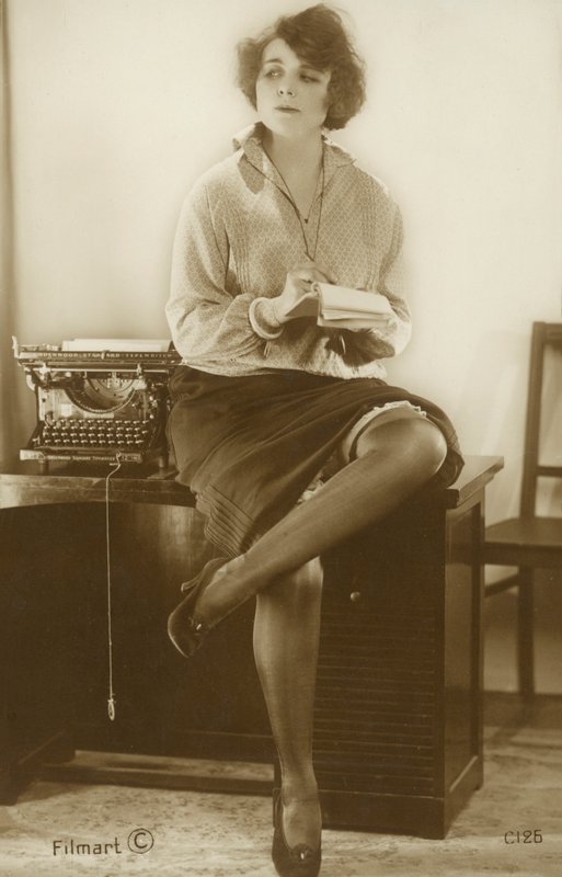 Secretaresse zittend op een bureau (z/w foto) door English Photographer