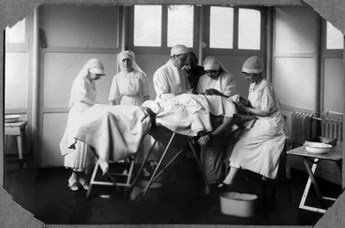 Eerste Wereldoorlog 1914-1918: artsen en verpleegsters van het Rode Kruis (Therese Pavillou?) behandelen een gewonde soldaat in het kamp van Couville in de Manche, Basse-Normandie, Frankrijk. Anonieme foto.