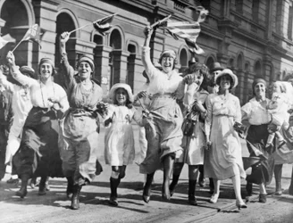 Een groep vrouwen en kinderen die in een straat in Sydney juichen bij de ondertekening van de wapenstilstand, 11 november 1918