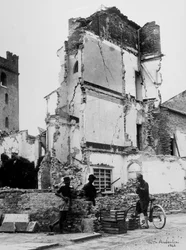 De bombardementen van Sermide. Drie mensen voor een groep gebombardeerde huizen
