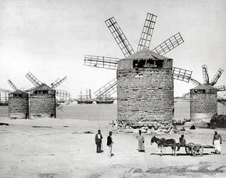 Windmolens aan de Middellandse Zee in Alexandrië, Egypte. Op de voorgrond poseren enkele Egyptenaren met een kleine kar