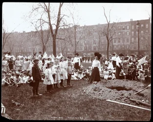 Volwassenen en kinderen met vlaggen staan rond een nieuw gegraven gat voor een boomplanting op Arbor Day in Tompkins Square Park, New York