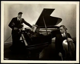 Blinde vrouw, Miss Harding, aan de piano die twee blinde mannen op de viool en cello instrueert, 1936