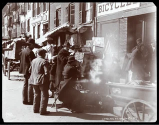 Uitzicht op straatverkopers, waaronder een die fotografische beelden van exotische plaatsen toont in een kijkdoos, op Bayard Street, New York, 1898