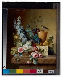 Een vaas met bloemen op een marmeren richel & een mand met bloemen met een distelvink