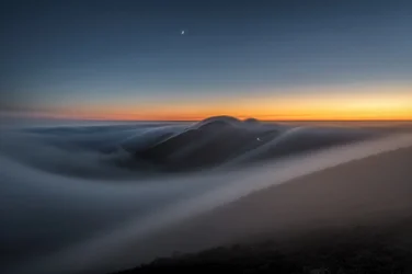 Schemerige bergen boven de wolken