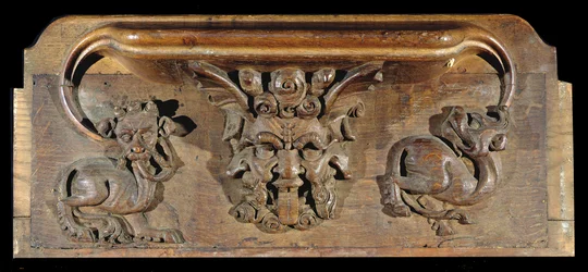 Een misericord die drie menselijke gezichten toont, geflankeerd door monsters, New College Chapel, Oxford, laat 14e eeuw (hout)